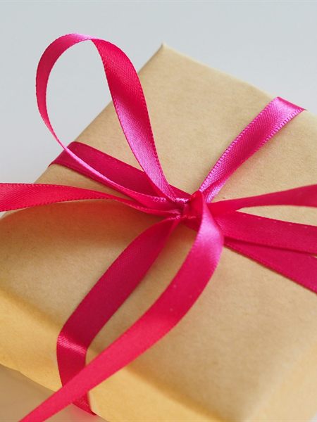 Caja de regalo forrada en papel kraft con un lazo rosa